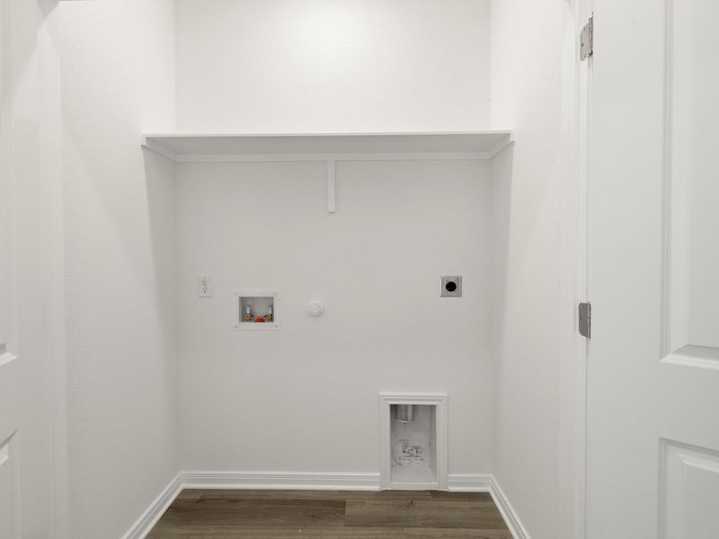 A dedicated laundry alcove with convenient hookups and a practical storage shelf.