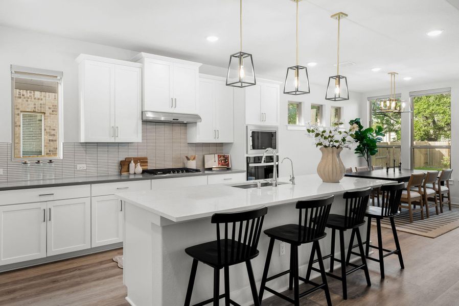A contemporary kitchen and dining area features abundant natural light, a kitchen island with seating, and integrated appliances.