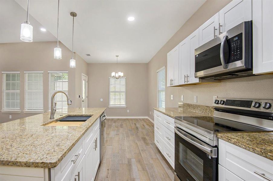 Kitchen with appliances with stainless steel finishes, light wood-style floors, recessed lighting, white cabinetry, and a chandelier