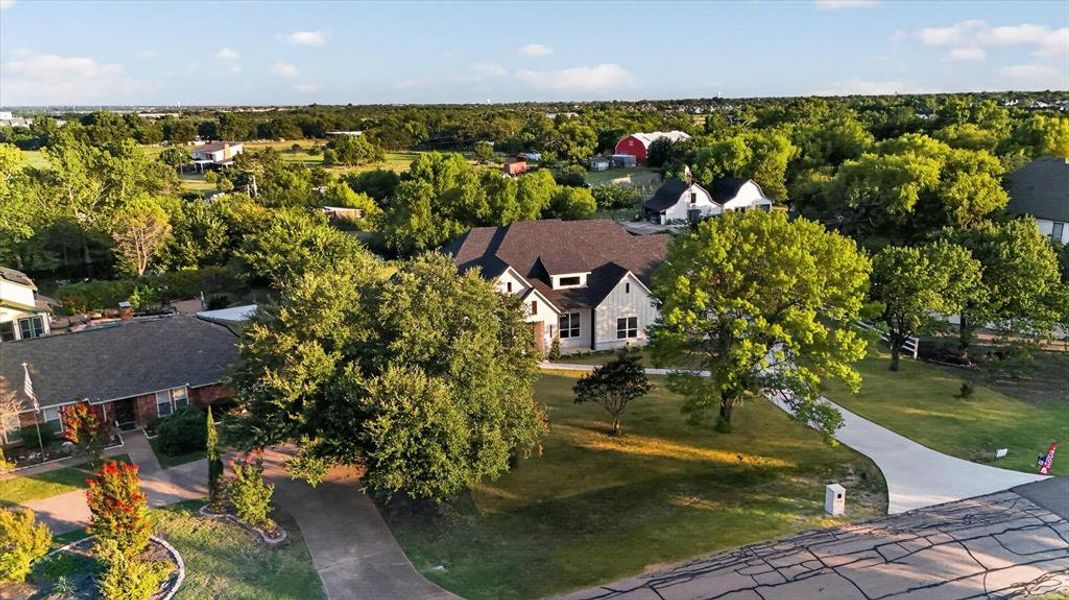 Expansive property featuring a contemporary home with a dark roof and light-colored siding, surrounded by mature trees Expansive property featuring a contemporary home with a dark roof and light-colored siding, surrounded by mature trees