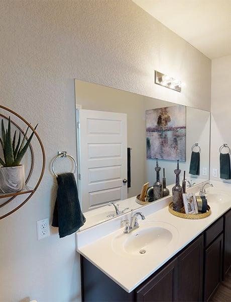 Full bath with double vanity and a textured wall