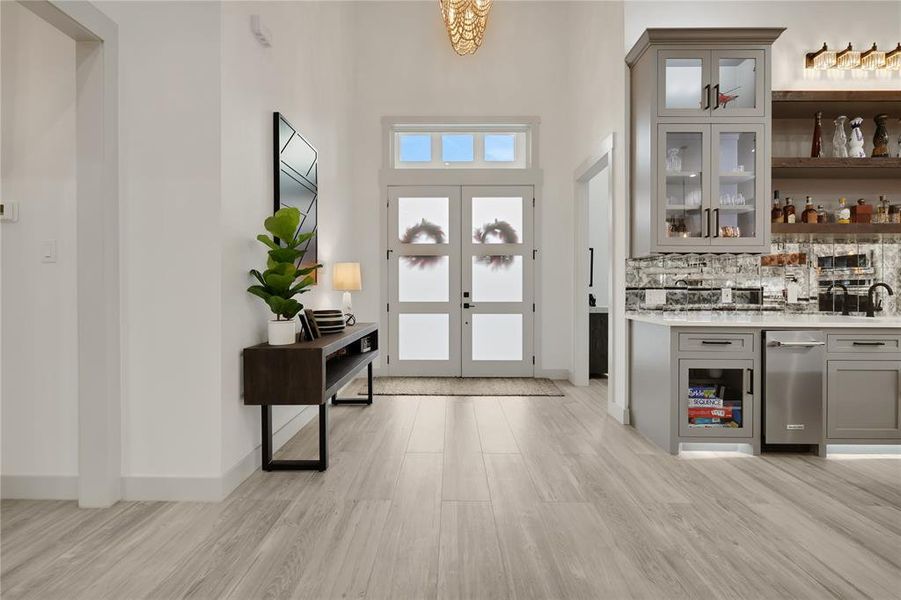 View from the family room to the double door entry. Music room is to the right behind the entertainment bar area. Owner's retreat is down the hall to the left in this photo. Split floor plan.