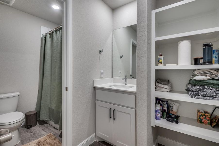 Bathroom with vanity, a textured wall, a closet, and built in features