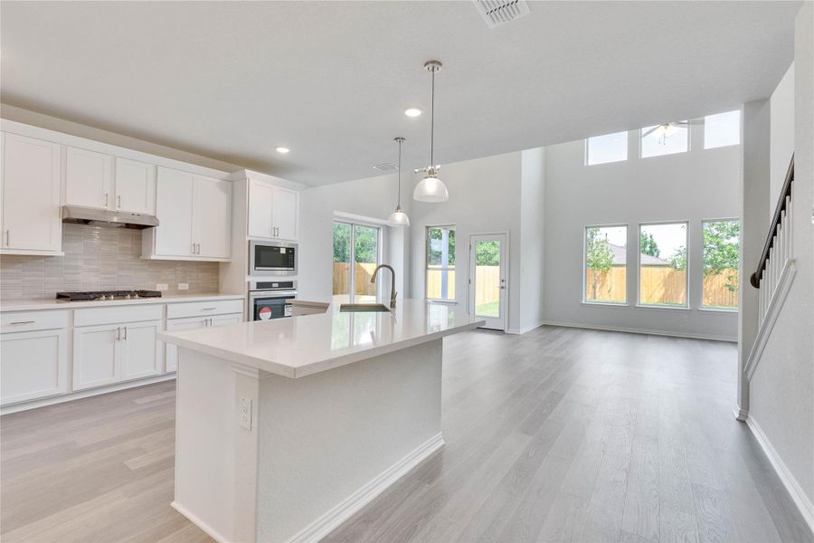 Kitchen with a sink, appliances with stainless steel finishes, light wood-style floors, light countertops, and under cabinet range hood Kitchen with a sink, appliances with stainless steel finishes, light wood-style floors, light countertops, and under cabinet range hood