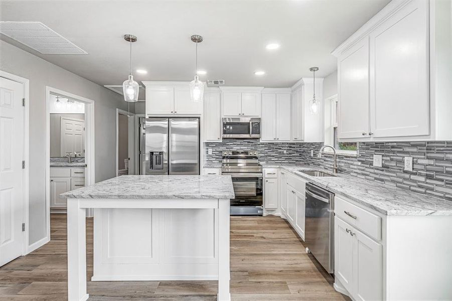 Kitchen with appliances with stainless steel finishes, a sink, light wood-type flooring, white cabinetry, and recessed lighting Kitchen with appliances with stainless steel finishes, a sink, light wood-type flooring, white cabinetry, and recessed lighting