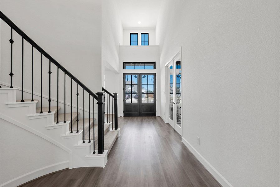 Foyer with a high ceiling, wood finished floors, baseboards, french doors, and stairway