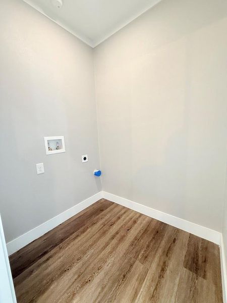 A dedicated utility space with durable wood flooring awaits laundry appliances.