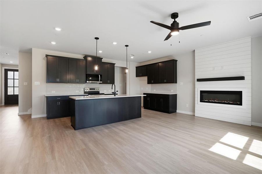 Kitchen featuring hanging light fixtures, light wood-style floors, a center island with sink, appliances with stainless steel finishes, and recessed lighting Kitchen featuring hanging light fixtures, light wood-style floors, a center island with sink, appliances with stainless steel finishes, and recessed lighting