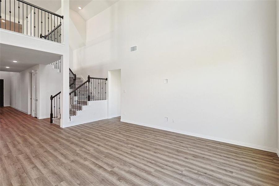 Unfurnished living room featuring a towering ceiling and hardwood / wood-style flooring