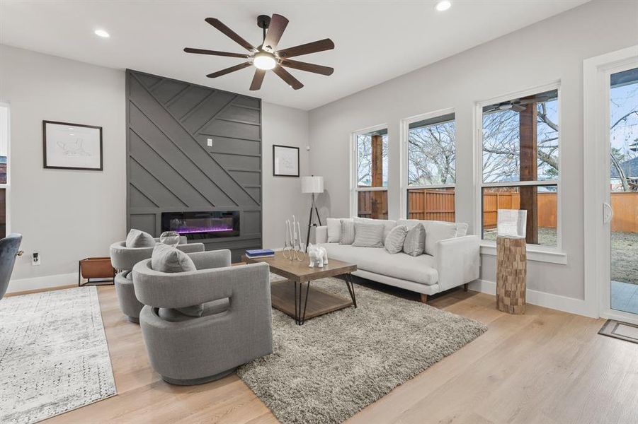 Living room with ceiling fan, a fireplace, and light wood-type flooring