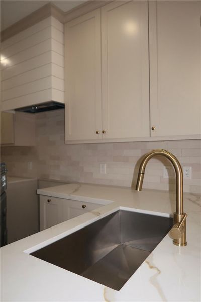The kitchen showcases a spacious undermount sink and a neutral color palette with elegant gold accents. The kitchen showcases a spacious undermount sink and a neutral color palette with elegant gold accents.