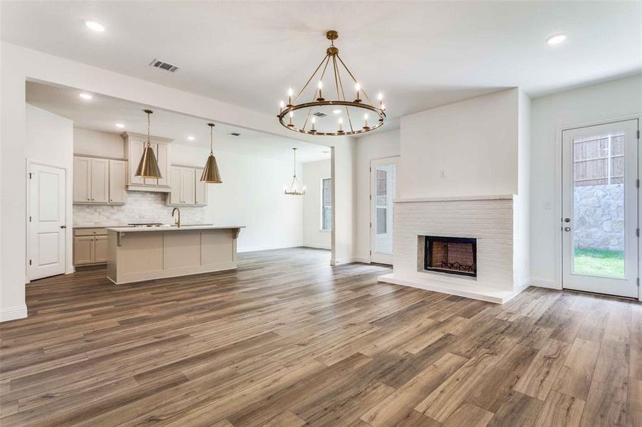 Unfurnished living room featuring a chandelier, wood finished floors, baseboards, a sink, and recessed lighting Unfurnished living room featuring a chandelier, wood finished floors, baseboards, a sink, and recessed lighting