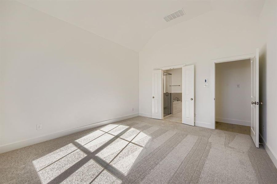 Unfurnished bedroom with light colored carpet, ensuite bathroom, and high vaulted ceiling Unfurnished bedroom with light colored carpet, ensuite bathroom, and high vaulted ceiling