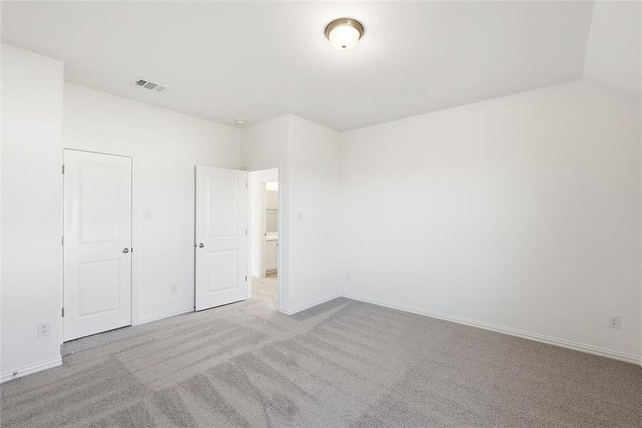 Spacious room featuring neutral carpeting, white baseboards, and two paneled doors