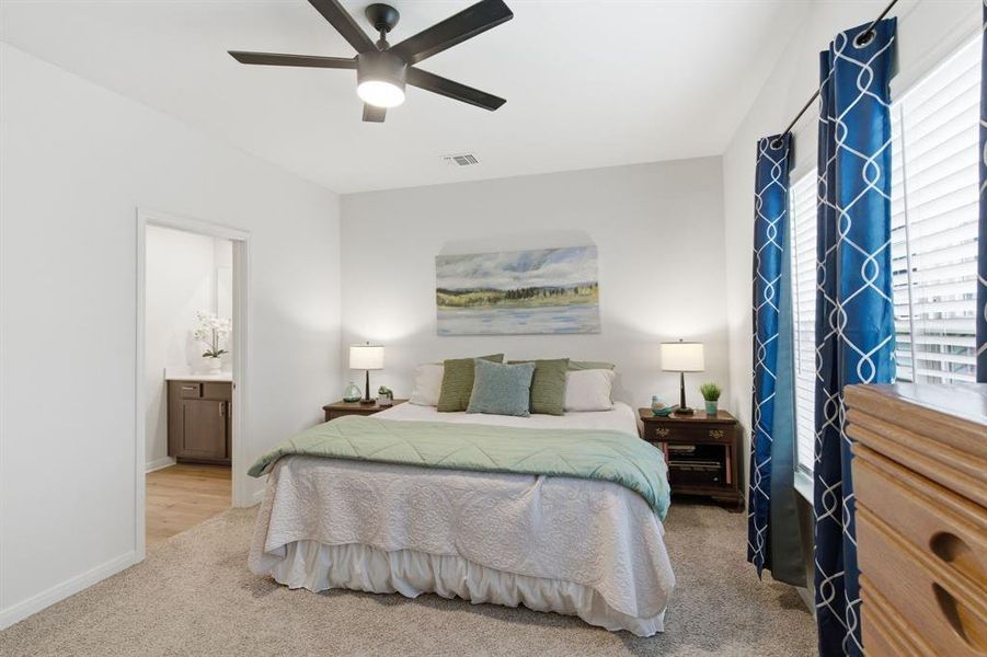 This bedroom features soft carpet flooring, a ceiling fan with integrated lighting, and windows with blinds