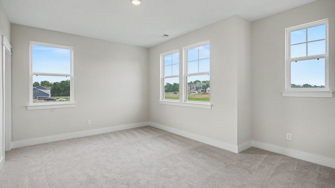 Secondary bedroom with windows and carpet