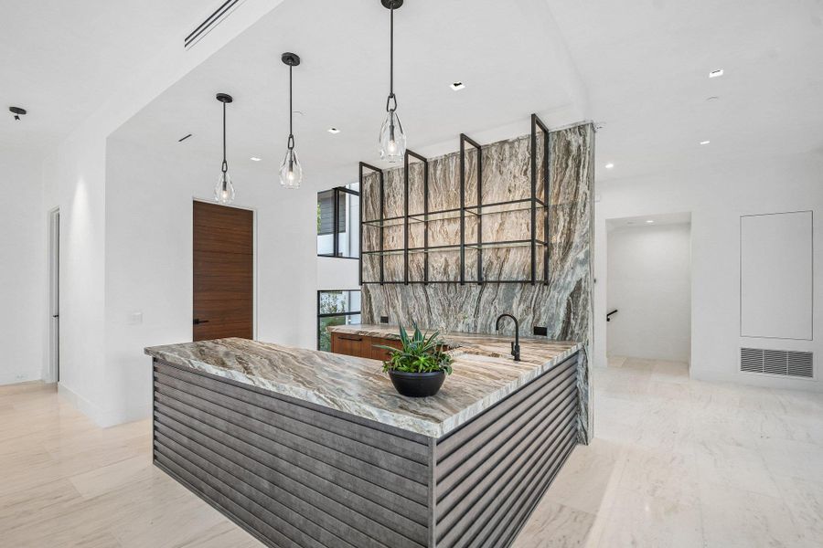 Striking natural stone surfaces and built-in metal shelving anchor this elegant wet bar. Striking natural stone surfaces and built-in metal shelving anchor this elegant wet bar.