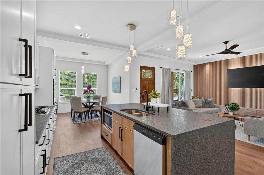 Open-concept kitchen featuring white cabinetry with matte black hardware, a large island with an undermount sink, and stone-finish countertops