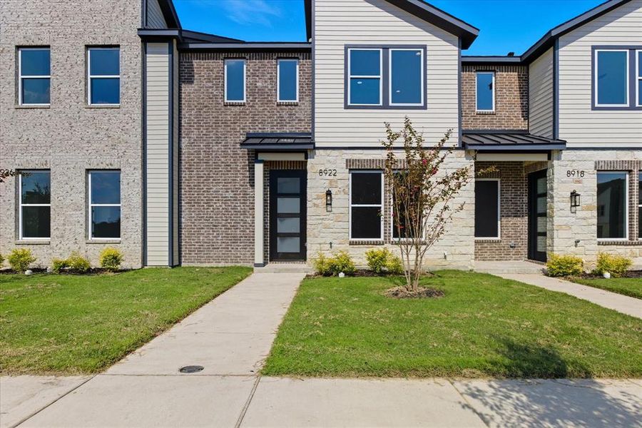 Contemporary home with a standing seam roof, brick siding, a front yard, and a metal roof