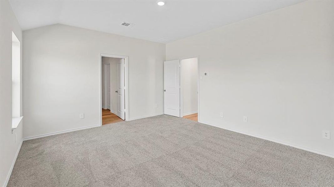 Unfurnished bedroom with light carpet and vaulted ceiling