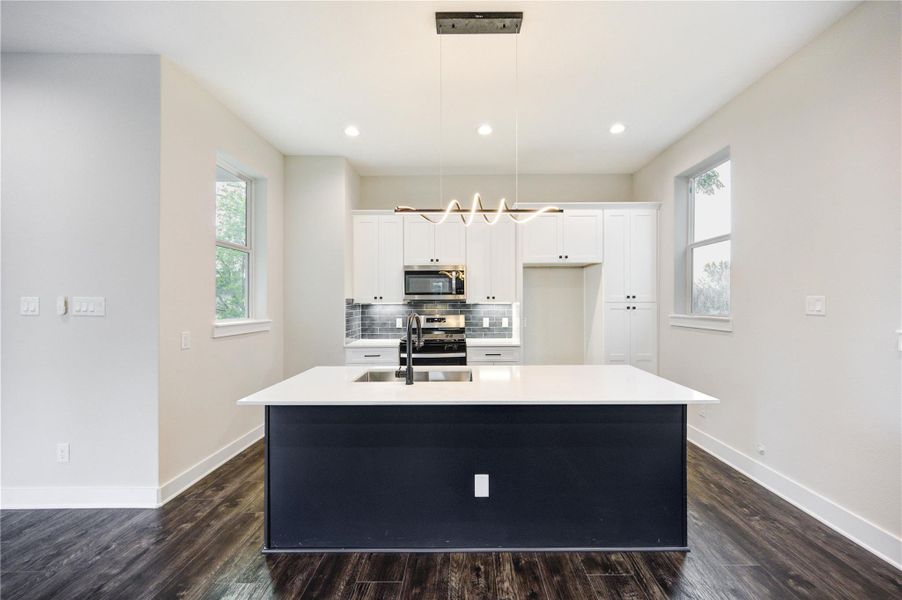 Light filled kitchen with two-tone cabinetry. quartz countertops and stainless-steel appliances. Large island with designer fixtures.