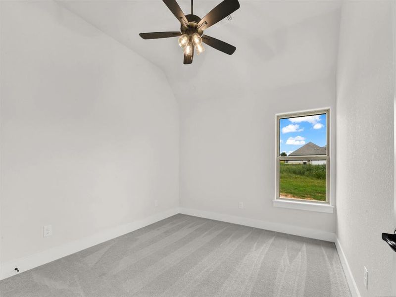 Empty room featuring light carpet, lofted ceiling, and ceiling fan