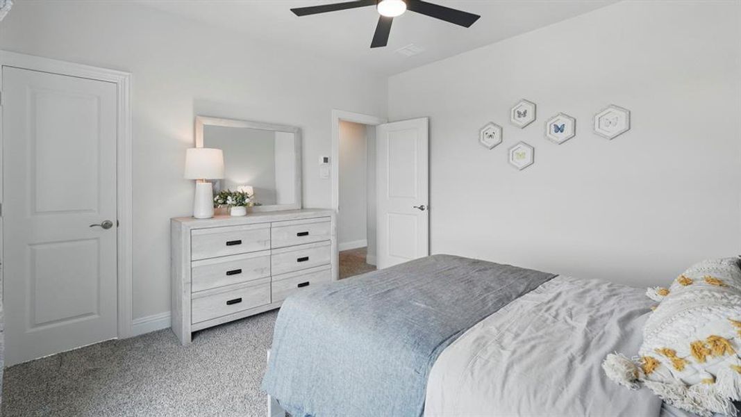 Bedroom featuring neutral gray wall paint, gray carpet flooring, a black ceiling fan with light, and white interior doors