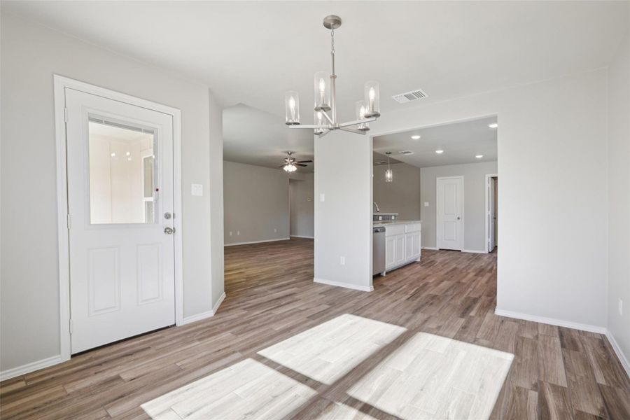 Unfurnished dining area featuring suspended lighting, a ceiling fan, and light wood finished floors