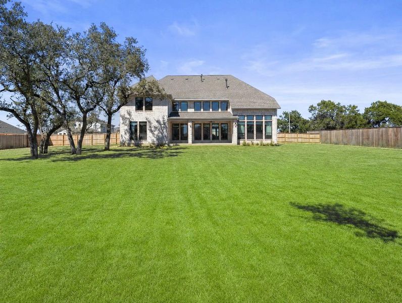 A well-maintained lawn stretches behind a residence with extensive window views. A well-maintained lawn stretches behind a residence with extensive window views.
