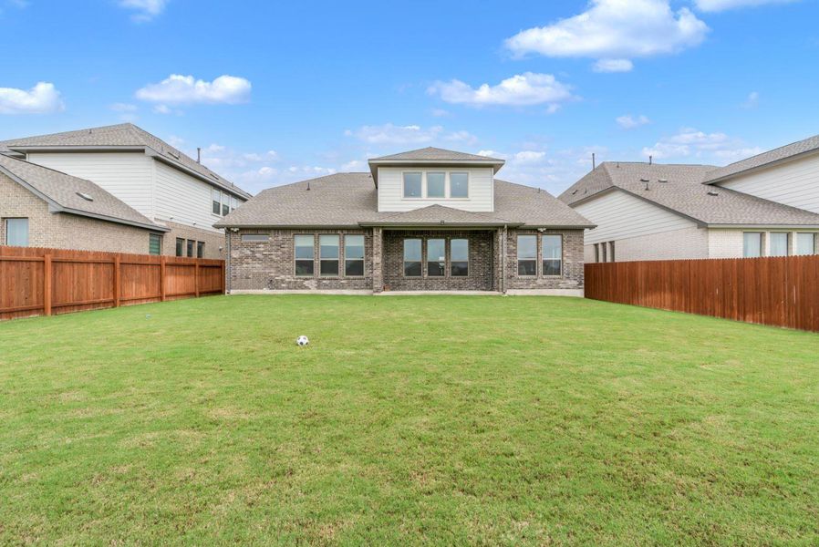 A vast green lawn provides ample space for recreation behind this attractive brick and siding residence.