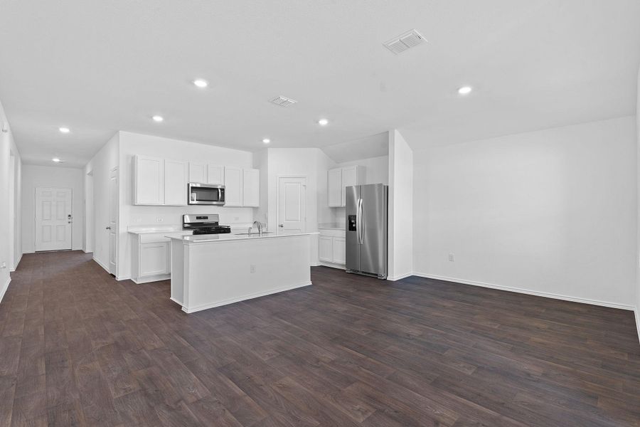 Kitchen featuring a kitchen island with sink, stainless steel appliances, a sink, white cabinets, and dark wood finished floors