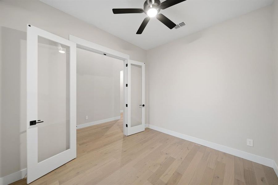 Unfurnished bedroom featuring light wood-style flooring, a ceiling fan, and french doors