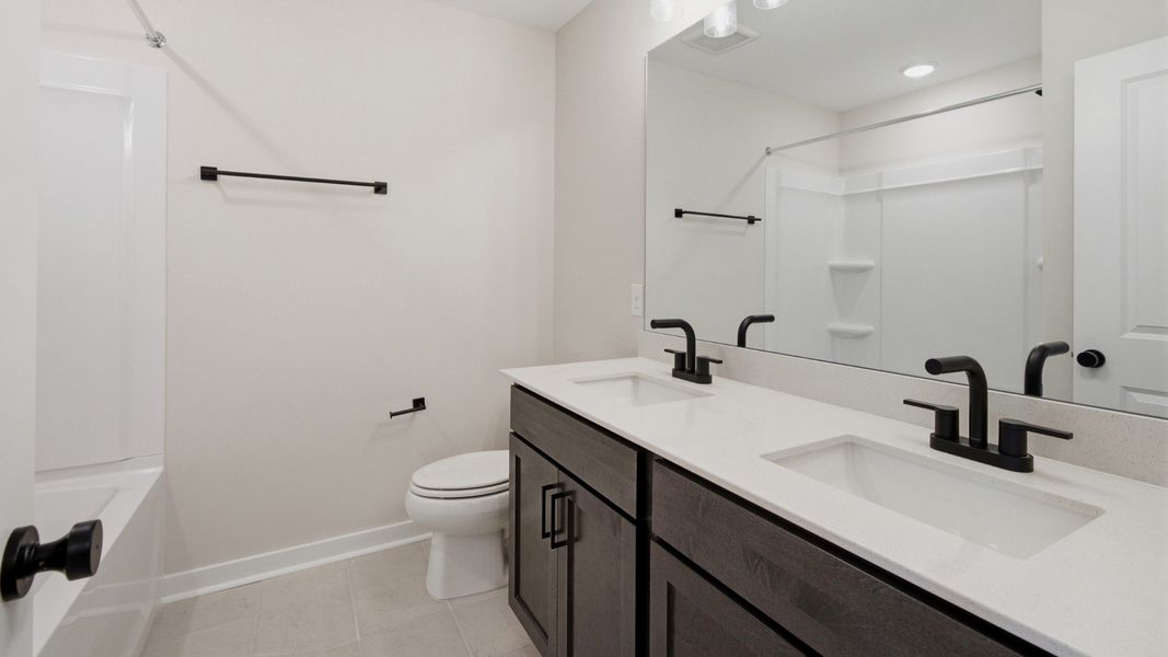 Bathroom with dual vanities across bathtub and shower