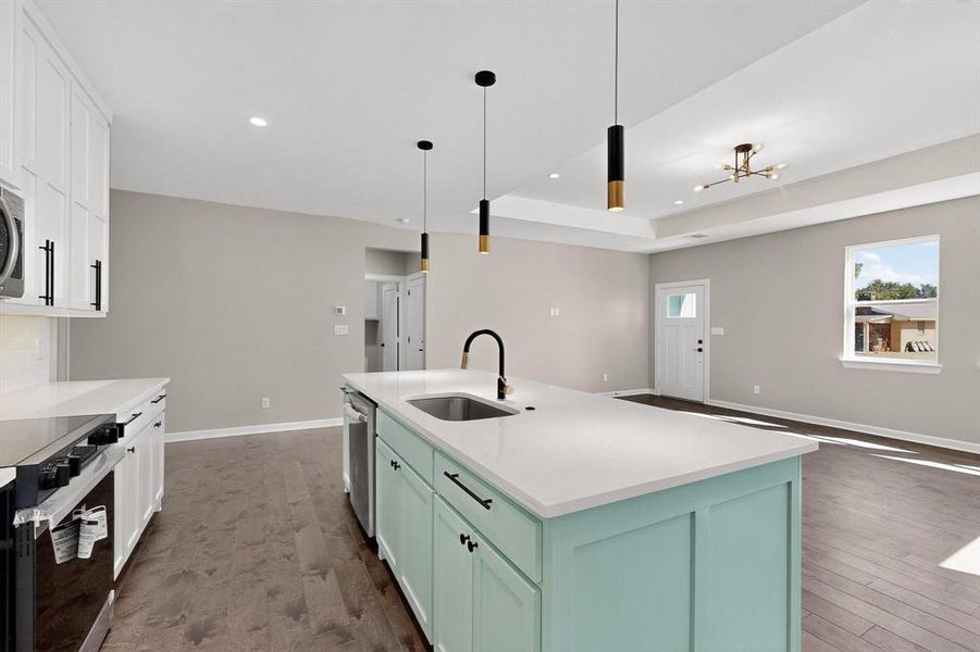 Kitchen featuring white cabinetry, decorative light fixtures, dark wood finished floors, light stone countertops, and a kitchen island with sink Kitchen featuring white cabinetry, decorative light fixtures, dark wood finished floors, light stone countertops, and a kitchen island with sink
