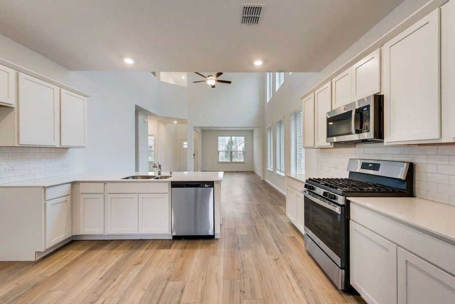 Kitchen featuring white cabinetry, backsplash, sink, ceiling fan, and appliances with stainless steel finishes