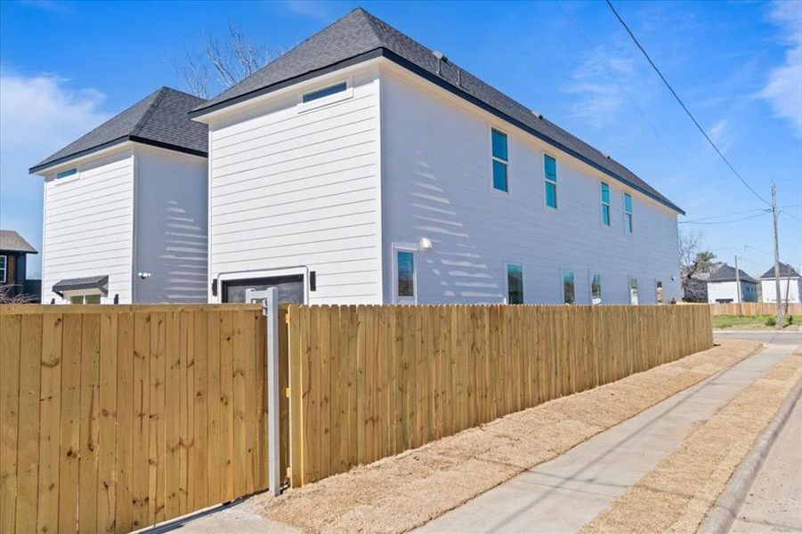 View of home's exterior with a shingled roof and fence