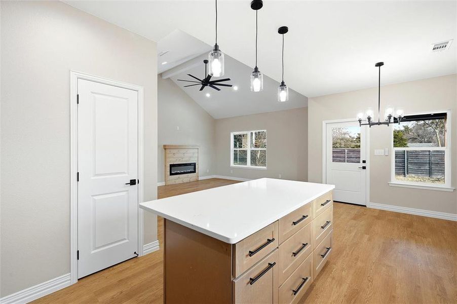 Kitchen with a fireplace, light countertops, a center island, light wood-style flooring, and a ceiling fan Kitchen with a fireplace, light countertops, a center island, light wood-style flooring, and a ceiling fan