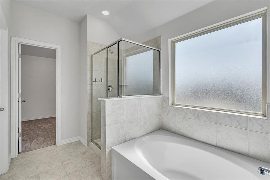 Bathroom with shower with separate bathtub and tile patterned flooring