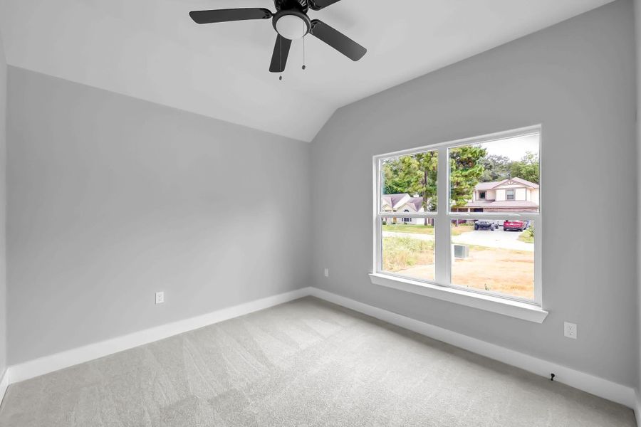 This is a bright, unfurnished room with neutral gray walls and soft carpeting. It features a large window offering plenty of natural light and a ceiling fan for comfort. This is a bright, unfurnished room with neutral gray walls and soft carpeting. It features a large window offering plenty of natural light and a ceiling fan for comfort.