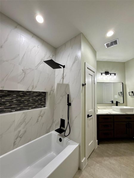 This modern bathroom features a sleek design with a marble-tiled shower and tub combo, accented by a recessed shelf with mosaic tiles. It has a rainfall showerhead, contemporary fixtures, and a stylish vanity with a large mirror. The lighting is recessed, providing a clean and bright ambiance. This modern bathroom features a sleek design with a marble-tiled shower and tub combo, accented by a recessed shelf with mosaic tiles. It has a rainfall showerhead, contemporary fixtures, and a stylish vanity with a large mirror. The lighting is recessed, providing a clean and bright ambiance.
