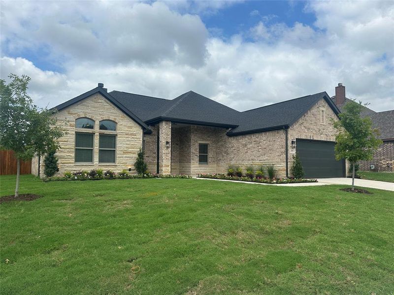 French country inspired facade featuring a garage and a front lawn