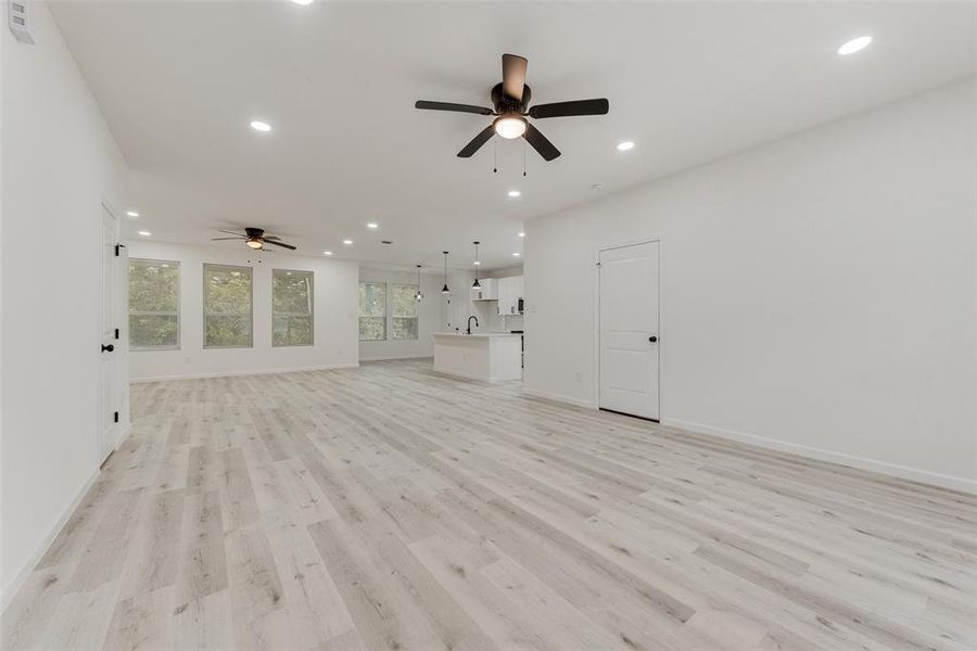 Unfurnished living room featuring ceiling fan, sink, and light hardwood / wood-style floors