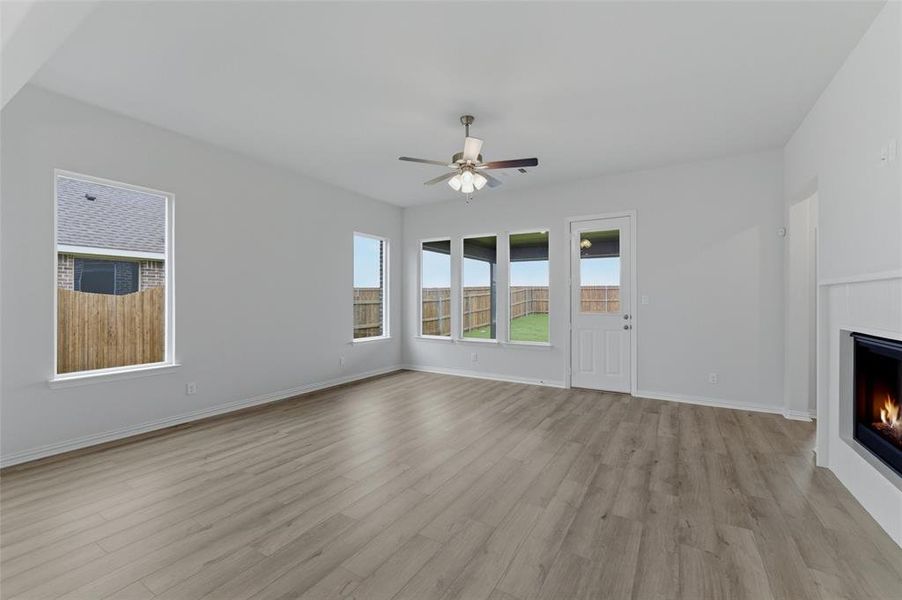 Spacious living area featuring wood-finish flooring, a ceiling fan, and a built-in fireplace with a white mantel