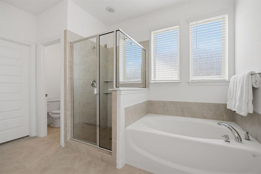Spa-inspired primary bath with soaking tub, separate glass shower, dual vanities, and natural light. A peaceful retreat inside this better-than-new Princeton, TX home at 905 Bluebell St.