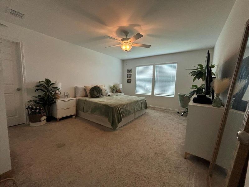 Carpeted bedroom with ceiling fan and baseboards