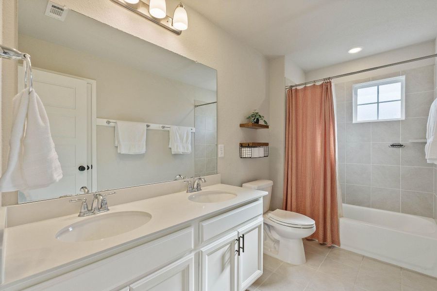 This bathroom features a modern, clean design with a double vanity, ample mirror space, and elegant lighting. It includes a bathtub with a shower, complemented with natural lighting. The neutral color palette and tiled flooring create a bright, inviting atmosphere. This bathroom features a modern, clean design with a double vanity, ample mirror space, and elegant lighting. It includes a bathtub with a shower, complemented with natural lighting. The neutral color palette and tiled flooring create a bright, inviting atmosphere.