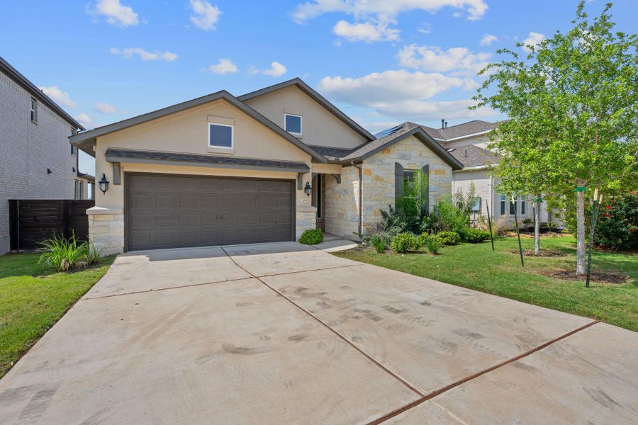 View of front of property featuring stone siding, stucco siding, concrete driveway, and an attached garage