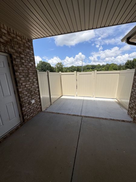 Covered patio with fence and storage closet.