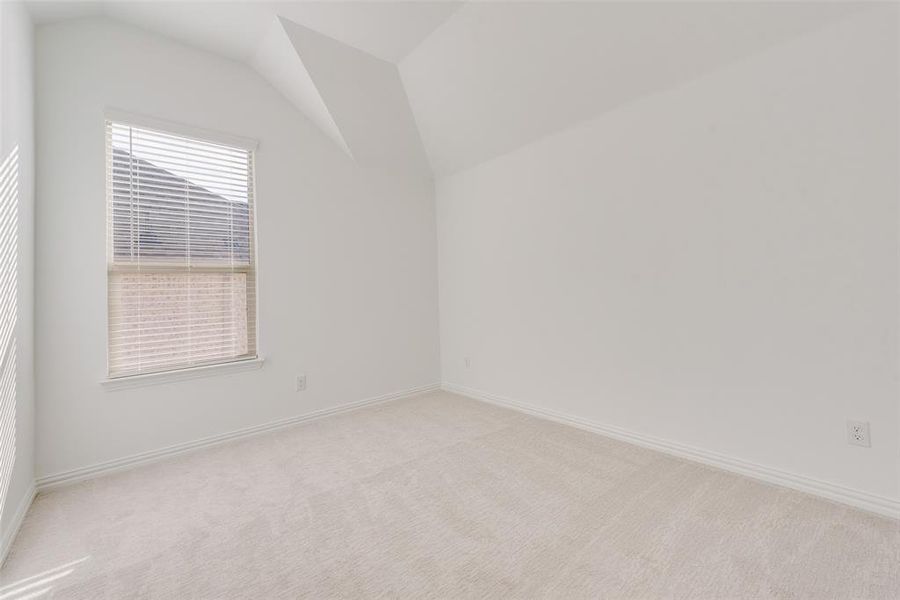 Carpeted empty room featuring lofted ceiling