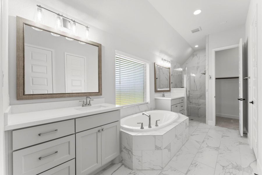 Frameless shower glass, elegant finishes, and a soaking tub make this primary bathroom sophisticated and serene. Frameless shower glass, elegant finishes, and a soaking tub make this primary bathroom sophisticated and serene.